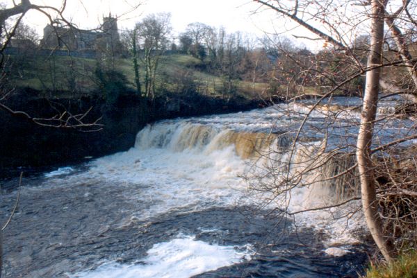 Aysgarth Falls Middle Drop Waterfall with St. Andrews Church on the horizon.